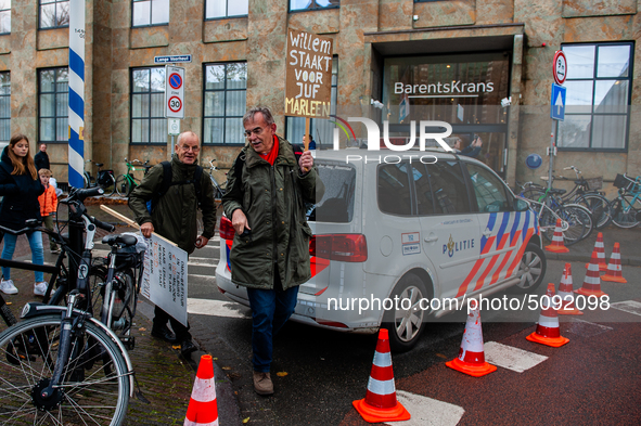 Two men are seen leaving the demonstration passing a police car, during the massive teachers demonstration that took place in The Hague, on...