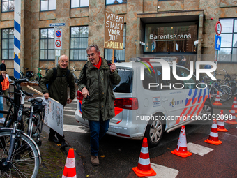 Two men are seen leaving the demonstration passing a police car, during the massive teachers demonstration that took place in The Hague, on...