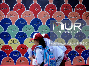 Children with Parents see education Graffiti themed walls in a narrow alley in Pademangan, Jakarta, November, 15,2019. Graffiti on the wall...