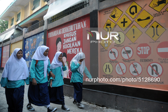 Children with Parents see education Graffiti themed walls in a narrow alley in Pademangan, Jakarta, November, 15,2019. Graffiti on the wall...