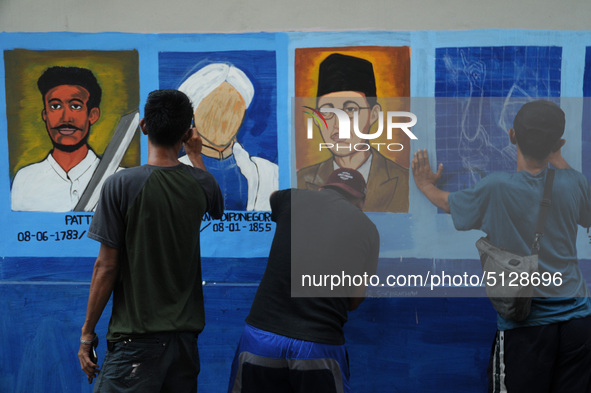 Children with Parents see education Graffiti themed walls in a narrow alley in Pademangan, Jakarta, November, 15,2019. Graffiti on the wall...