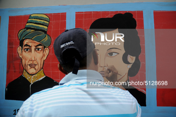 Children with Parents see education Graffiti themed walls in a narrow alley in Pademangan, Jakarta, November, 15,2019. Graffiti on the wall...