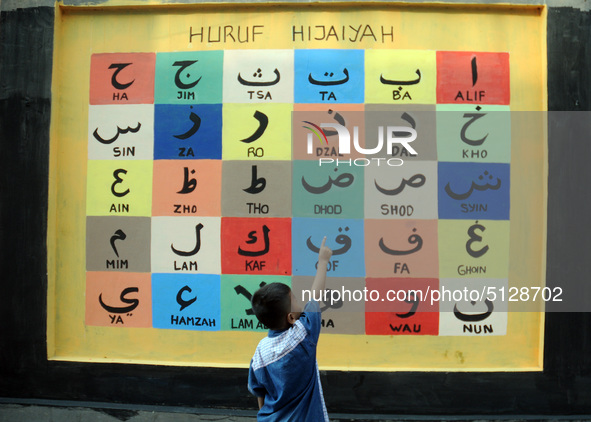 Children with Parents see education Graffiti themed walls in a narrow alley in Pademangan, Jakarta, November, 15,2019. Graffiti on the wall...