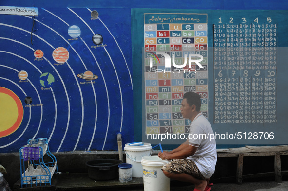 Children with Parents see education Graffiti themed walls in a narrow alley in Pademangan, Jakarta, November, 15,2019. Graffiti on the wall...