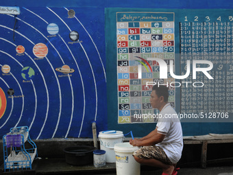 Children with Parents see education Graffiti themed walls in a narrow alley in Pademangan, Jakarta, November, 15,2019. Graffiti on the wall...