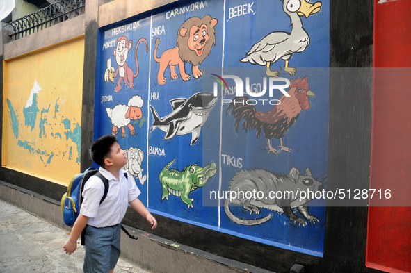 Children with Parents see education Graffiti themed walls in a narrow alley in Pademangan, Jakarta, November, 15,2019. Graffiti on the wall...