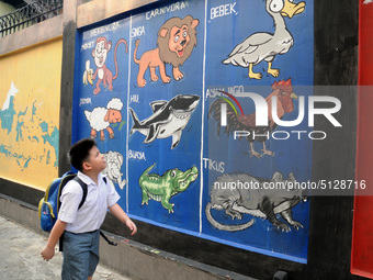 Children with Parents see education Graffiti themed walls in a narrow alley in Pademangan, Jakarta, November, 15,2019. Graffiti on the wall...