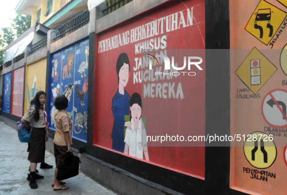 Children with Parents see education Graffiti themed walls in a narrow alley in Pademangan, Jakarta, November, 15,2019. Graffiti on the wall...