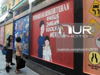 Children with Parents see education Graffiti themed walls in a narrow alley in Pademangan, Jakarta, November, 15,2019. Graffiti on the wall...