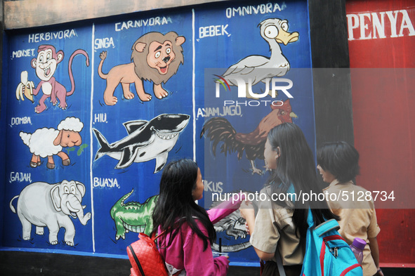 Children with Parents see education Graffiti themed walls in a narrow alley in Pademangan, Jakarta, November, 15,2019. Graffiti on the wall...