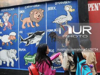 Children with Parents see education Graffiti themed walls in a narrow alley in Pademangan, Jakarta, November, 15,2019. Graffiti on the wall...