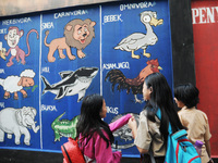 Children with Parents see education Graffiti themed walls in a narrow alley in Pademangan, Jakarta, November, 15,2019. Graffiti on the wall...