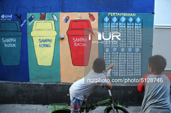 Children with Parents see education Graffiti themed walls in a narrow alley in Pademangan, Jakarta, November, 15,2019. Graffiti on the wall...