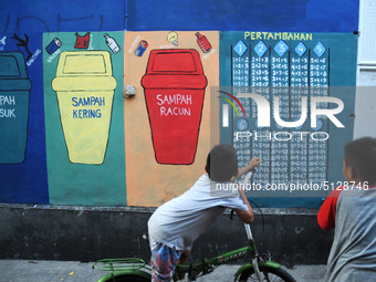 Children with Parents see education Graffiti themed walls in a narrow alley in Pademangan, Jakarta, November, 15,2019. Graffiti on the wall...