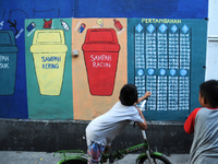 Children with Parents see education Graffiti themed walls in a narrow alley in Pademangan, Jakarta, November, 15,2019. Graffiti on the wall...