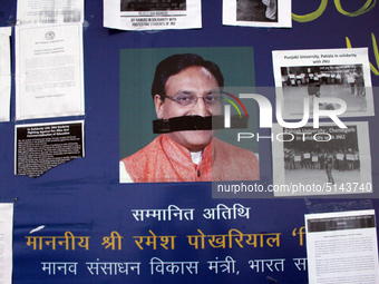 A defaced poster of Union Minister of Human Resource Development Ramesh Pokhriyal is seen as students protest against the hostel fee hike, a...