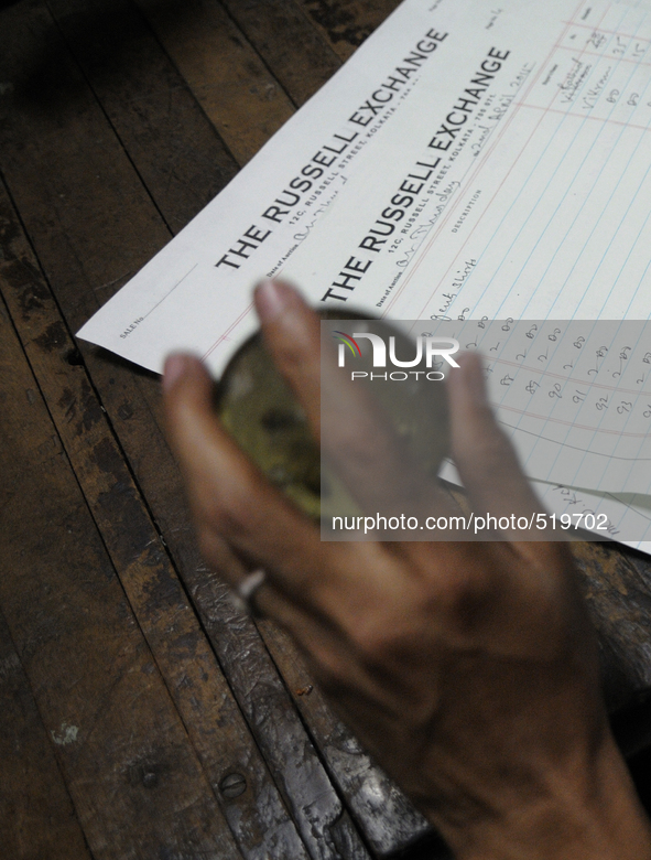 Sheikh Samsuddinan employee of The Russell Exchange knocking a paper weight on a table beside a log book which keeps the information of the...