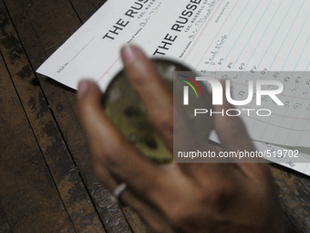 Sheikh Samsuddinan employee of The Russell Exchange knocking a paper weight on a table beside a log book which keeps the information of the...