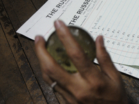 Sheikh Samsuddinan employee of The Russell Exchange knocking a paper weight on a table beside a log book which keeps the information of the...