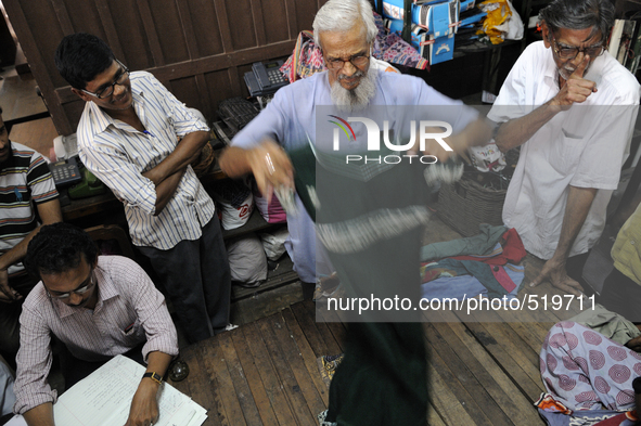 Ayub Mallik an employee of the Russell Exchange showing old clothes to the buyers while Sheikh Samsuddinan (L) busy writing the information...