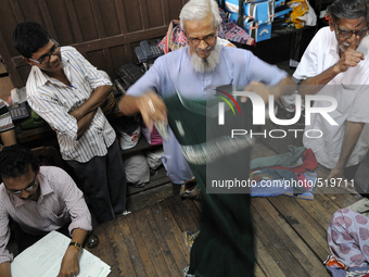 Ayub Mallik an employee of the Russell Exchange showing old clothes to the buyers while Sheikh Samsuddinan (L) busy writing the information...