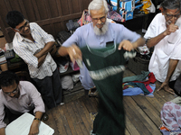 Ayub Mallik an employee of the Russell Exchange showing old clothes to the buyers while Sheikh Samsuddinan (L) busy writing the information...