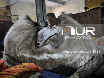 Mr. Khan a clothing vendor on the streets of Kolkata folding a "sari" that he bought during the old clothes auction at The Russell Exchange...