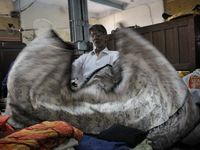 Mr. Khan a clothing vendor on the streets of Kolkata folding a "sari" that he bought during the old clothes auction at The Russell Exchange...