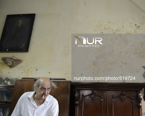 Anwar Saleem the elder brother with a cigarette in front of an old painting and an old piece of furniture during the old clothes auction at...