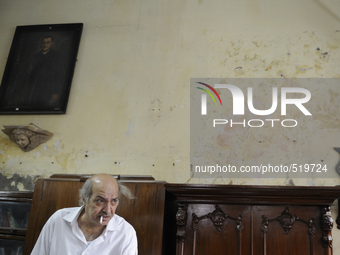 Anwar Saleem the elder brother with a cigarette in front of an old painting and an old piece of furniture during the old clothes auction at...