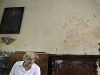 Anwar Saleem the elder brother with a cigarette in front of an old painting and an old piece of furniture during the old clothes auction at...