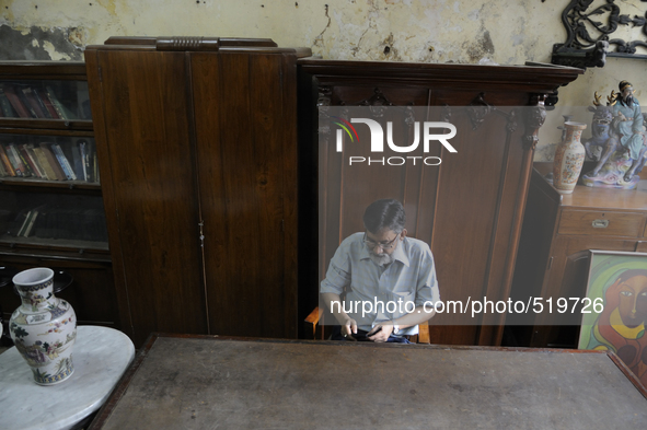 Mumtaz Ali an employee of The Russell Exchange checking his  while sitting in front of a 60 year old wooden furniture made out of "shagun wo...