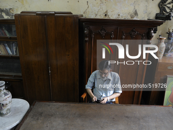 Mumtaz Ali an employee of The Russell Exchange checking his  while sitting in front of a 60 year old wooden furniture made out of "shagun wo...