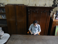 Mumtaz Ali an employee of The Russell Exchange checking his  while sitting in front of a 60 year old wooden furniture made out of "shagun wo...