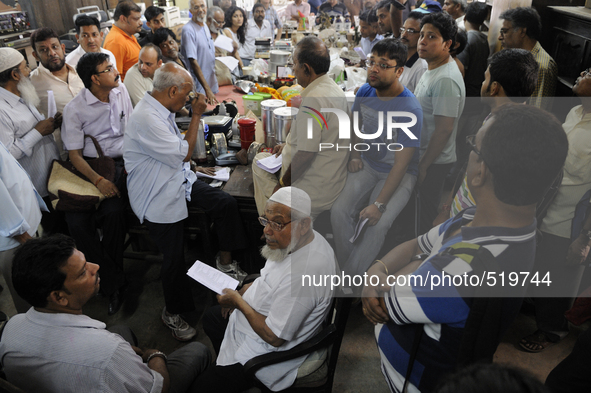 Mr. Reheman ( sitting in the middle) a regular well off customer  seeing the list which has the items names and numbers to match the items a...