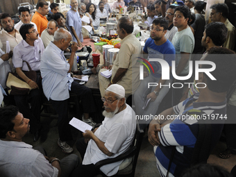 Mr. Reheman ( sitting in the middle) a regular well off customer  seeing the list which has the items names and numbers to match the items a...