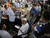 Mr. Reheman ( sitting in the middle) a regular well off customer  seeing the list which has the items names and numbers to match the items a...