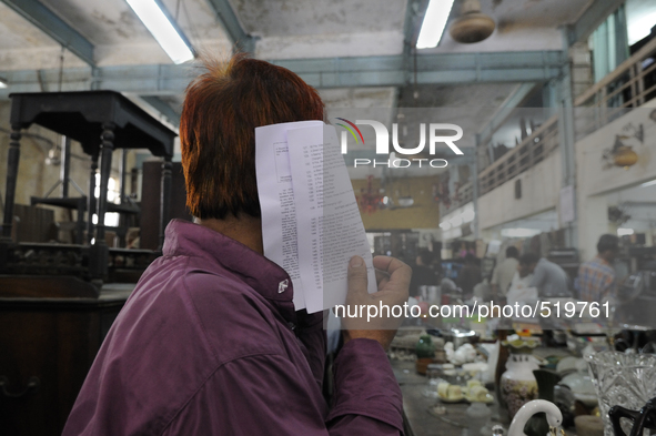 A customer hiding his face with the check list of items ( the piece of computer generated piece of paper used every week) during the Auction...