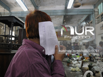 A customer hiding his face with the check list of items ( the piece of computer generated piece of paper used every week) during the Auction...