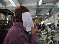 A customer hiding his face with the check list of items ( the piece of computer generated piece of paper used every week) during the Auction...