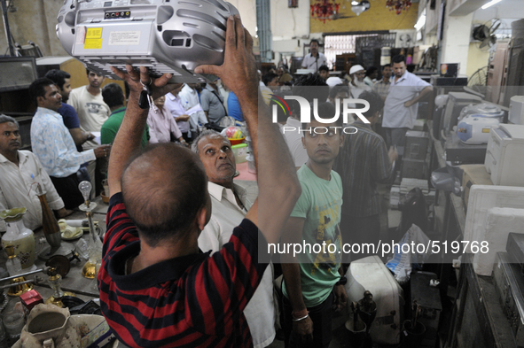 Munna (guy with red and black t-shirt) an electronic dealer lifting an electronics item for others to see during an  auction at The Russell...