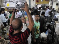 Munna (guy with red and black t-shirt) an electronic dealer lifting an electronics item for others to see during an  auction at The Russell...