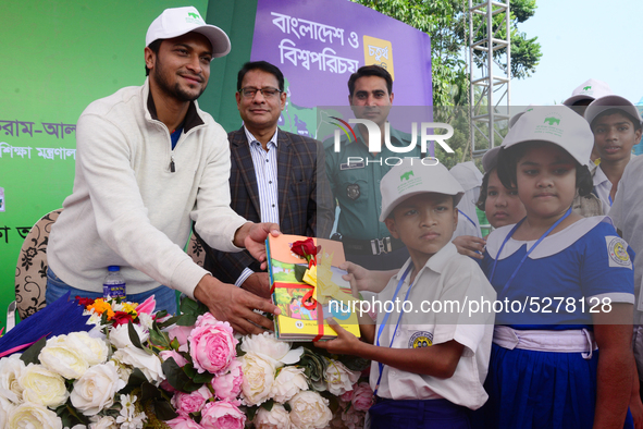 Bangladeshi Cricketer Shakib Al Hasan (L) distributing textbooks among students at the Dhaka University sports ground as the government kick...