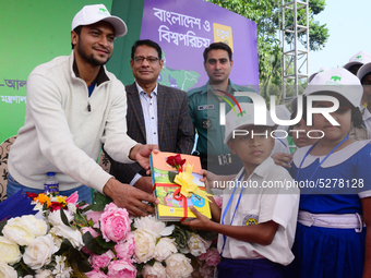 Bangladeshi Cricketer Shakib Al Hasan (L) distributing textbooks among students at the Dhaka University sports ground as the government kick...