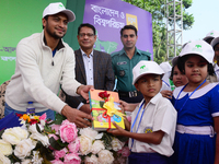 Bangladeshi Cricketer Shakib Al Hasan (L) distributing textbooks among students at the Dhaka University sports ground as the government kick...