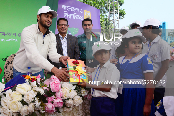 Bangladeshi Cricketer Shakib Al Hasan (L) distributing textbooks among students at the Dhaka University sports ground as the government kick...