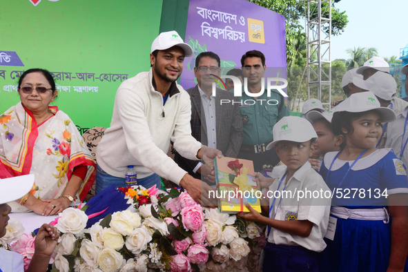 Bangladeshi Cricketer Shakib Al Hasan (L) distributing textbooks among students at the Dhaka University sports ground as the government kick...