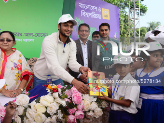 Bangladeshi Cricketer Shakib Al Hasan (L) distributing textbooks among students at the Dhaka University sports ground as the government kick...