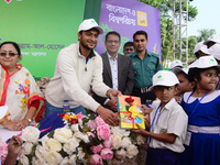 Bangladeshi Cricketer Shakib Al Hasan (L) distributing textbooks among students at the Dhaka University sports ground as the government kick...