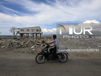 Drivers pass in front of a house damaged by the tsunami in Kampung Lere Beach, Palu Bay, Central Sulawesi, Indonesia on January 9, 2020. The...